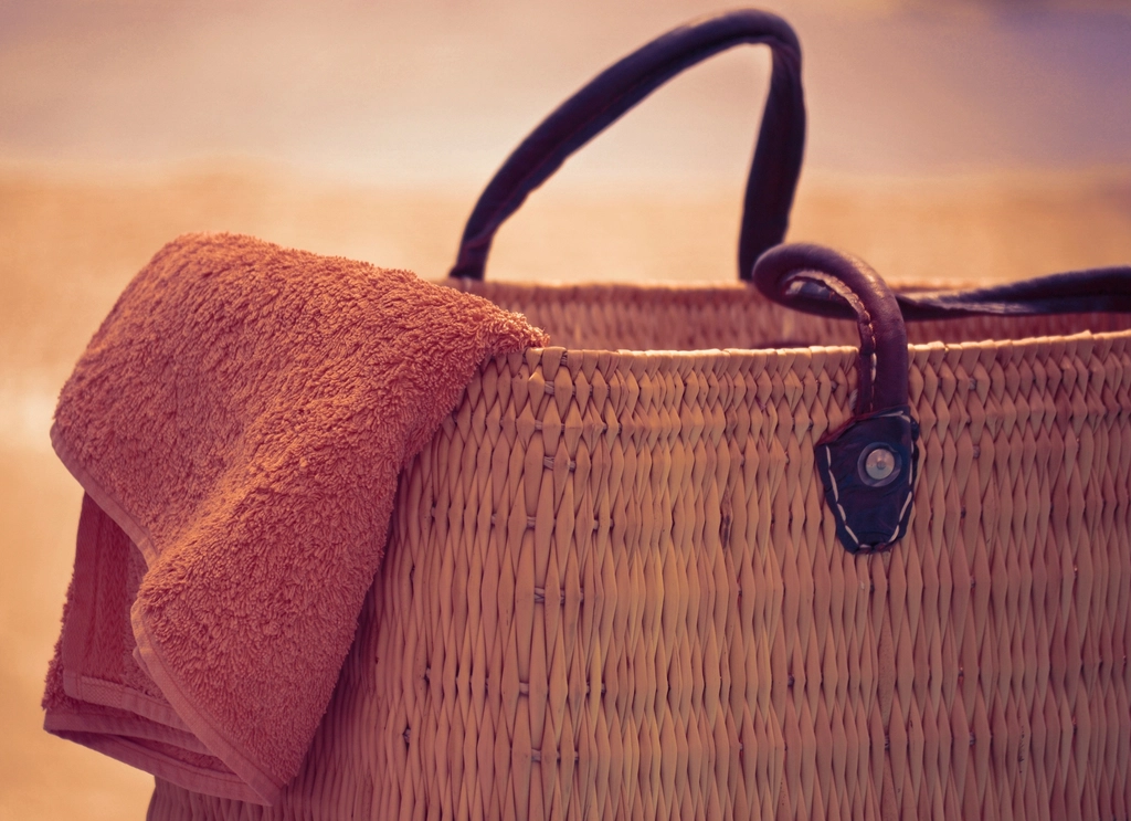 Woven beach bag with towel in warm summer light