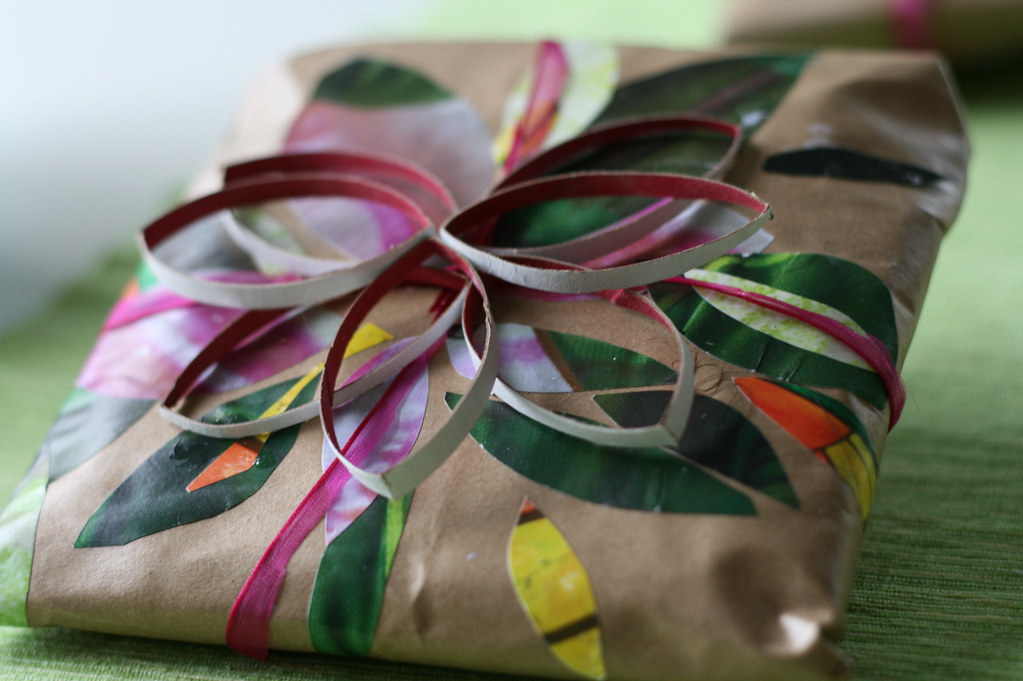 Hand-wrapped gift with botanical paper and ribbon on a green surface