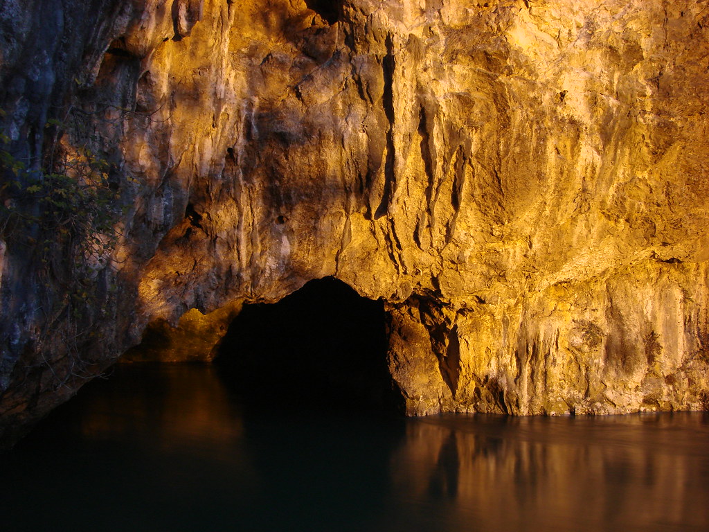Warm golden cave entrance reflected in calm water