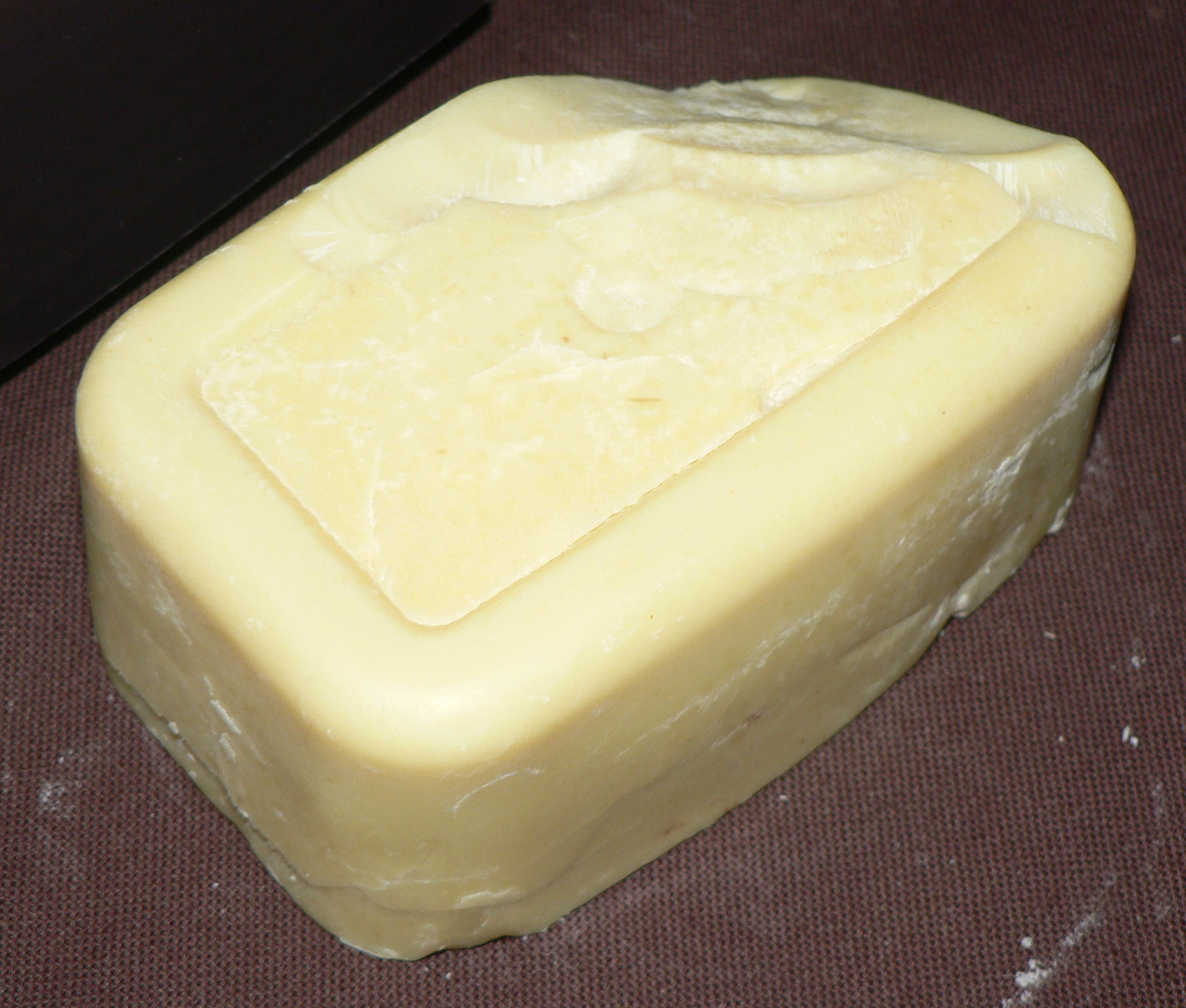 Pale cocoa butter block on a dark cloth for a clean beauty ingredient guide