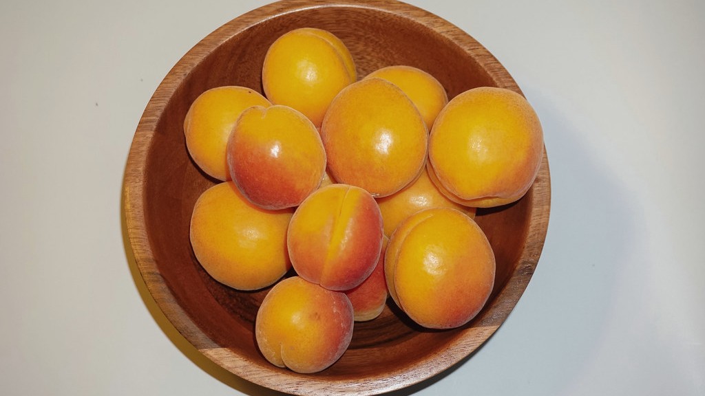 Fresh apricots arranged in a wooden bowl for an apricot kernel oil ingredient guide