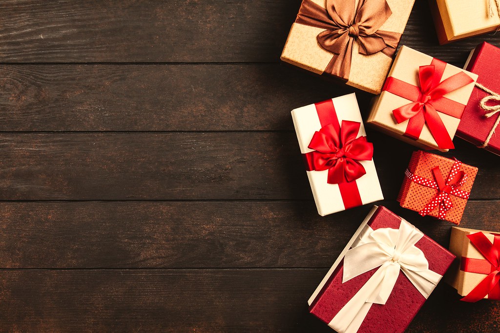 Wrapped holiday gifts with red ribbons on a dark wood table