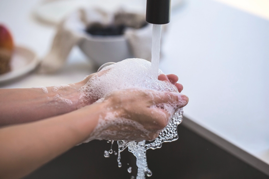 Hands holding a mound of soap bubbles beneath running water