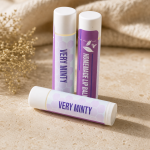 Three Plumera Very Minty handmade lip balm tubes with purple and white labels on a black background