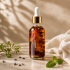 Amber botanical oil in a clear glass dropper bottle with visible dried flowers