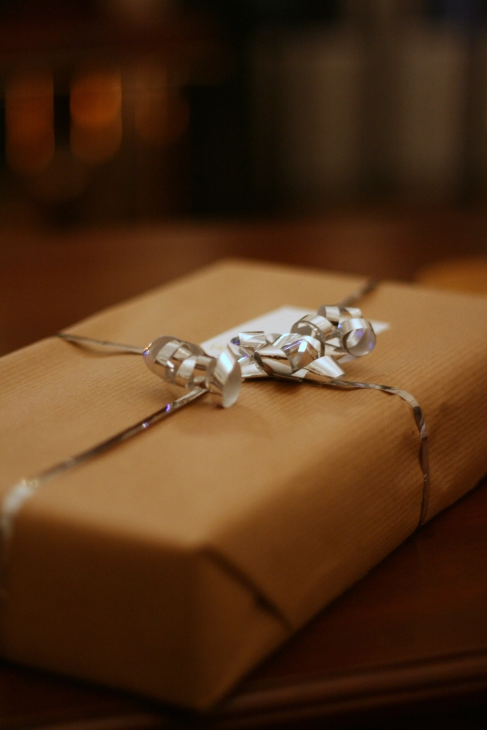 Kraft-paper housewarming gift wrapped with silver ribbon in warm light