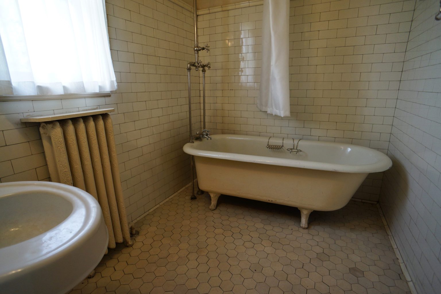 Vintage bathtub and open tiled floor in a sunlit bathroom